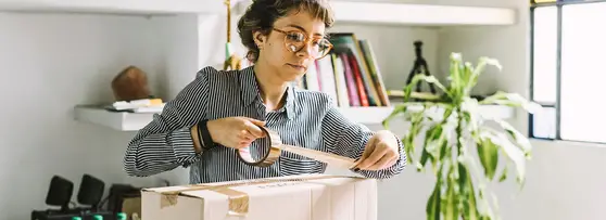 woman taping up a package in her home office